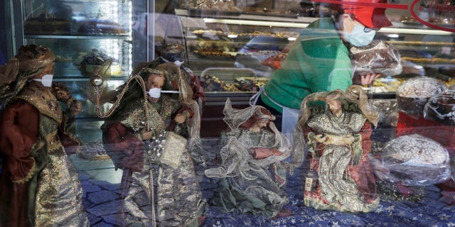 Statuettes of the Wise Kings wearing face masks adorn, along with the Nativity scene, the shop window of a pastry shop selling the traditional Italian Christmas cake, Panettone, in Rome, Wednesday, Dec. 3, 2020. Italy is bracing for new restrictive measures during Christmas and New Year. Prime Minister Giuseppe Conte is expected to sign a new decree on Thursday following a cabinet meeting held on Wednesday night. The rules will likely prevent Italians from traveling across the country during this season holidays in an effort to avoid a new wave of contagion. (AP Photo/Gregorio Borgia