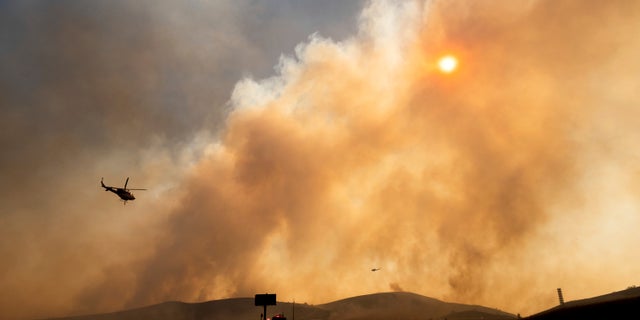 Smoke from the Bond Fire billows above State Route 241 in Orange County, Calif., on Thursday, Dec. 3, 2020. (AP Photo/Noah Berger)