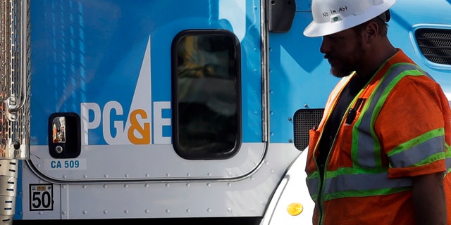FILE - In this Aug. 15, 2019, file photo, a Pacific Gas & Electric worker walks in front of a truck in San Francisco. (AP Photo/Jeff Chiu, File)