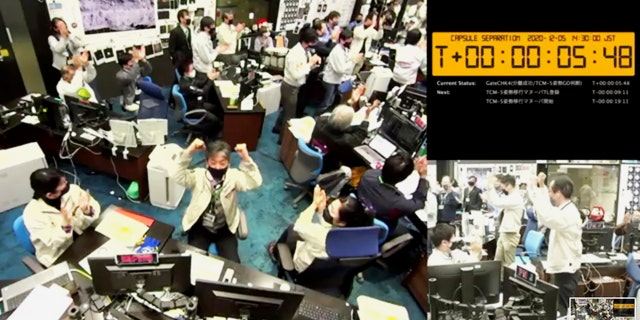 In this image from a video provided by the Japan Aerospace Exploration Agency (JAXA), its members react at the command center in Sagamihara, west of Tokyo, on Saturday, December 5, 2020, after JAXA officials confirmed the successful separation of a capsule from the Hayabusa2 spacecraft. (JAXA via AP)