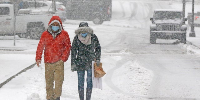 File photo - A couple walking through heavy snow, Saturday 5 December 2020, in downtown Marlborough, Mass.  The northeastern United States sees the first major snowstorm of the season.