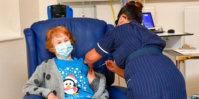 Margaret Keenan, 90, is the first patient in the UK to receive the Pfizer-BioNTech COVID-19 vaccine, administered by nurse May Parsons at University Hospital, Coventry, England, (Jacob King/Pool via AP)