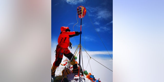 A member of a Chinese surveying team sets up survey equipment on the summit of Mount Everest, also known locally as Mt. Qomolangma. China and Nepal have jointly announced on Tuesday, Dec. 8, 2020, a new height for Mount Everest, ending a discrepancy between the two nations. (Tashi Tsering/Xinhua via AP, File)