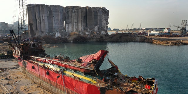 A destroyed ship lies near towering grain silos gutted in the massive August explosion at the Beirut port that claimed the lives of more than 200 people, in Beirut, Lebanon, Wednesday, Dec. 2, 2020. (AP Photo/Hussein Malla)