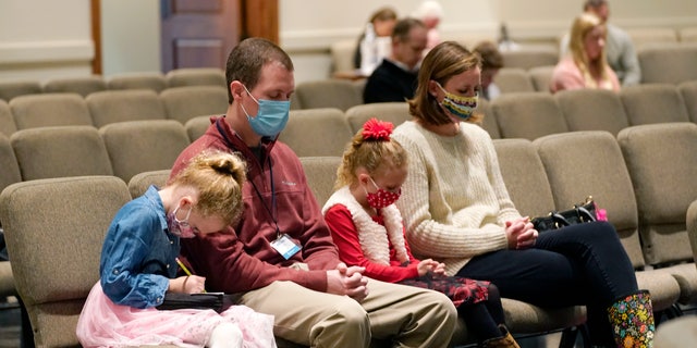 Jonathan and Alesha Vaughn, and their children, Addison, 5, left, and Ann Marie, 7, pray during services in the Worship Center at Highland Colony Baptist Church in Ridgeland, Miss., Nov. 29, 2020. (Associated Press)