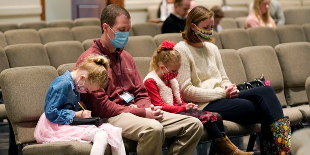 Jonathan Vaughn, second from left, and his family, Addison, 5, sinistra, Ann Marie, 7, second from right, and wife Alesha Vaughn pray during services in the Worship Center at Highland Colony Baptist Church in Ridgeland, Miss., Nov. 29, 2020. The church practices covid protocols by allowing families to sit spaced out from others, separating older and more vulnerable members in the worship hall and providing sanitizer and masks at the entrance. (AP Photo/Rogelio V. Solis)