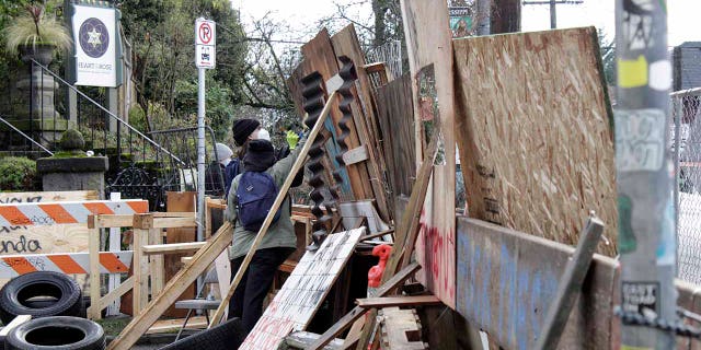 Protesters reinforce their barricades at an encampment outside a home in Portland, Ore., on Wednesday, Dec. 9, 2020. (AP Photo/Gillian Flaccus)