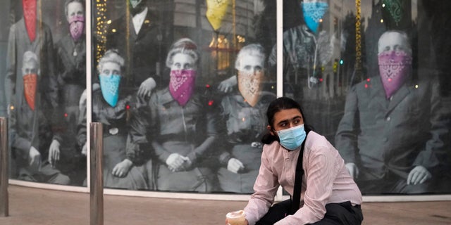 A man takes a coffee break in front of a COVID 19-themed mural, Wednesday, Dec. 9, 2020, in Beverly Hills, Calif. (AP Photo/Marcio Jose Sanchez)