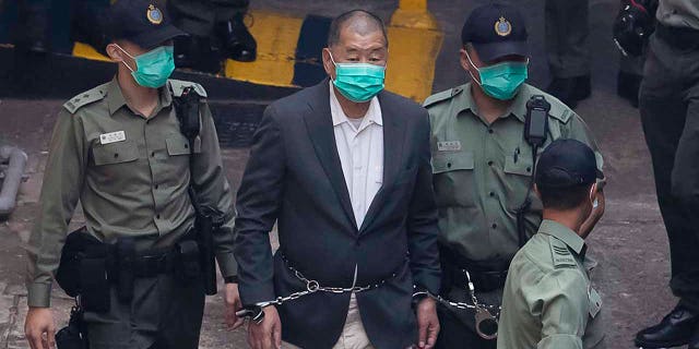 Hong Kong pro-democracy activist and media tycoon Jimmy Lai is escorted by Correctional Services officers to get on a prison van before appearing in a court in Hong Kong Dec. 12, 2020.