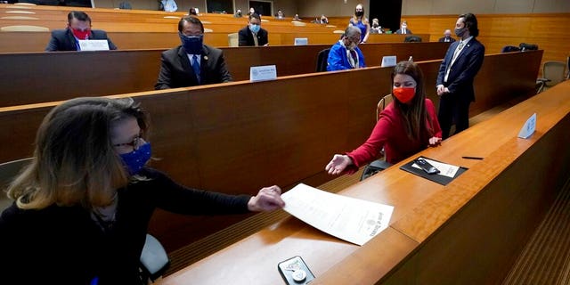 Regina Romero, right, and Felecia Rotellini, left, members of Arizona's Electoral College, exchange the Arizona Presidential Electoral Ballot as they sign their names to the certificate Monday, Dec. 14, 2020, in Phoenix. (AP Photo/Ross D. Franklin, Pool)