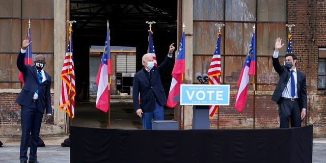 President-elect Joe Biden, center, acknowledges supporters at the end of a drive-in rally for Georgia Democratic candidates for U.S. Senate Raphael Warnock, left, and Jon Ossoff, Tuesday, Dec. 15, 2020, in Atlanta. (AP Photo/Patrick Semansky)