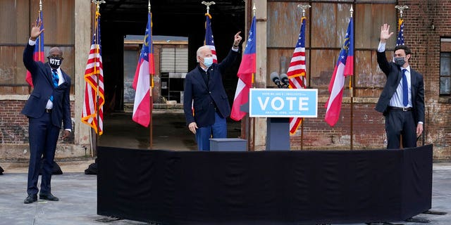 President-elect Joe Biden, center, acknowledges supporters at the end of a drive-in rally for Georgia Democratic candidates for U.S. Senate Raphael Warnock, left, and Jon Ossoff, Tuesday, Dec. 15, 2020, in Atlanta. (AP Photo/Patrick Semansky)
