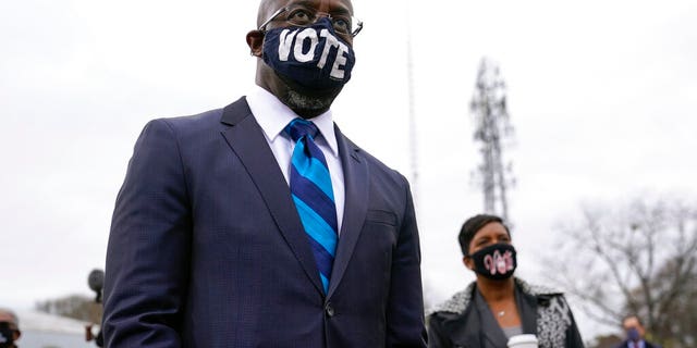 Georgia Democratic candidate for U.S. Senate Raphael Warnock listens as President-elect Joe Biden speaks at a drive-in rally for Warnock and Jon Ossoff, Dec. 15, in Atlanta. (AP Photo/Patrick Semansky)