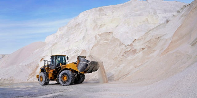 A front loader works at a large pile of road salt, Wednesday, Dec. 16, 2020, in Chelsea, Mass., as preparation continues for a storm that is expected to dump a foot or more of snow throughout the Northeast. (AP Photo/Elise Amendola)