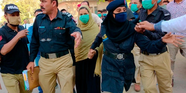 Police officers escort Arzoo Raja, 中央, a teenage Christian girl, who was allegedly abducted and forced to convert and marry a 44-year old Muslim, while they leave after an appearance before the High Court in Karachi, 巴基斯坦, 十一月. 3, 2020. (AP Photo/Fareed Khan)