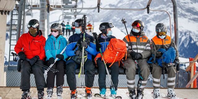 A policewoman and policeman (center) ride a ski lift as they patrol on the slopes and in alpine restaurants specifically, to check the application of sanitary measures during the coronavirus disease (COVID-19) outbreak, in the alpine resort of Villars-sur-Ollon, Switzerland, Saturday, December 19, 2020. The police receives local support of the "protection civile", civil protection (right), in alpine resort. (Valentin Flauraud/Keystone via AP)