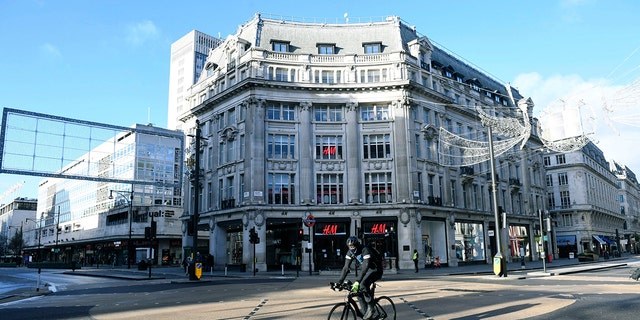 A cyclist passes Oxford Circus after Britian's Prime Minister Boris Johnson introduced Tier 4 restrictions for London and the southeast of the country, in London, Sunday, Dec. 20, 2020. Millions of people in England have learned they must cancel their Christmas get-togethers and holiday shopping trips. (Stefan Rousseau/PA via AP)