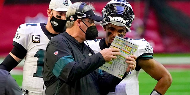 Philadelphia Eagles head coach Doug Pederson talks with starting quarterback Jalen Hurts as quarterback Carson Wentz (11) looks on during the first half of an NFL football game, Sunday, Dec. 20, 2020, in Glendale, Ariz. (AP Photo/Rick Scuteri)