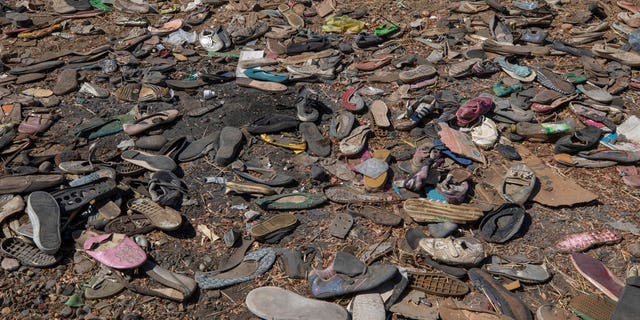 Shoes left behind belonging to Tigrayan refugees are scattered near the banks of the Tekeze River on the Sudan-Ethiopia border after Ethiopian forces blocked people from crossing into Sudan, in Hamdayet, eastern Sudan, Tuesday, Dec. 15, 2020. (AP Photo/Nariman El-Mofty)