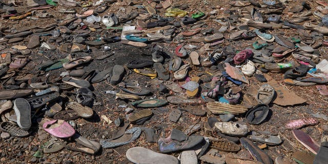 Shoes left behind belonging to Tigrayan refugees are scattered near the banks of the Tekeze River on the Sudan-Ethiopia border after Ethiopian forces blocked people from crossing into Sudan, in Hamdayet, eastern Sudan, Tuesday, Dec. 15, 2020. (AP Photo/Nariman El-Mofty)