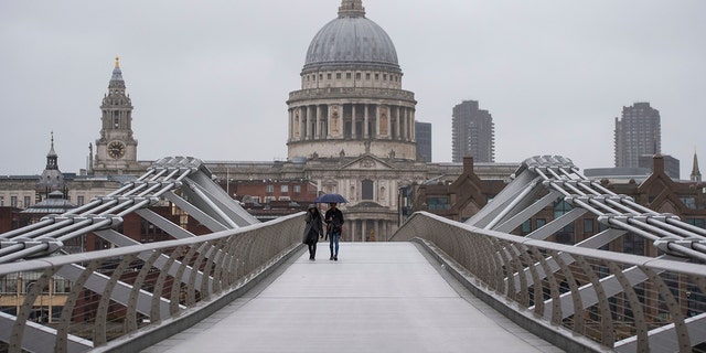 People walk across the Millennium Bridge in London, Monday, Dec. 21, 2020. Millions of people in England have learned they must cancel their Christmas get-togethers and holiday shopping trips. (Dominic Lipinski/PA via AP)