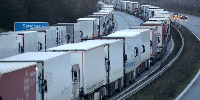 Trucks are parked along the M20 motorway where freight traffic is halted whilst the Port of Dover remains closed, in Ashford, Kent, England, Tuesday, Dec. 22, 2020. Trucks waiting to get out of Britain backed up for miles and people were left stranded at airports as dozens of countries around the world slapped tough travel restrictions on the U.K. because of a new and seemingly more contagious strain of the coronavirus in England. (Andrew Matthews/PA via AP)