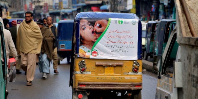 An auto rickshaw with a poster advertising a polio campaign drives through a market in Peshawar, Pakistan. Pakistan, Afghanistan and Nigeria are the only countries in the world where polio is still endemic. Lack of trust in vaccinations is one of many obstacles that will face public health officials in poor and developing countries as they seek to vaccinate millions of people against COVID-19. (AP Photo/Muhammad Sajjad)