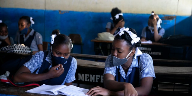 FILE - In this Aug. 17, 2020, file photo, students read at Lycee Marie Jeanne school in Port-au-Prince, Haiti, on their first day back to school amid the COVID-19 pandemic. Haiti, the Western Hemisphere’s poorest country, has yet to announce any COVID-19 vaccination plans. Health experts worry that widespread rumors could set back vaccinations -- including claims that hospitals will give fatal injections to inflate COVID-19 death figures and receive more foreign aid. (AP Photo/Dieu Nalio Chery, File)