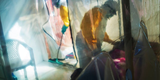 FILE - In this July 13, 2019, file photo, health workers wearing protective suits tend to an Ebola victim kept in an isolation tent in Beni, Democratic Republic of Congo. The task of vaccinating millions of people in poor and developing countries against COVID-19 faces monumental obstacles, and it's not just a problem of affording and obtaining doses. Rumors flew about the Ebola vaccines, including the idea they were meant to kill people, said Dr. Maurice Kakule, an Ebola survivor who worked in vaccination campaigns. Similar suspicions are spreading about the COVID-19 vaccine, he said. (AP Photo/Jerome Delay, File)