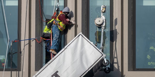 A worker stands at the end of a suspended scaffolding as he waits to be rescued following an explosion at the offices of Baltimore Gas and Electric on Wednesday.  Twenty-one of the victims were transported to hospitals in the area following the blast with partial roof collapse.  City firefighters tweeted that at least nine of the victims were in critical condition, while another was in serious condition.  (Jerry Jackson / The Baltimore Sun via AP)