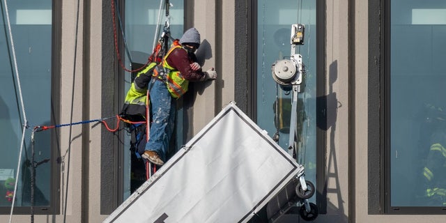 A worker stands on the end of a dangling scaffold as he waits to be rescued following an explosion at Baltimore Gas and Electric's offices, on Wednesday. Twenty-one of the victims were brought to area hospitals following the explosion with a partial roof collapse. The city’s fire department tweeted that at least nine of the victims were in critical condition, while another was in serious condition. (Jerry Jackson/The Baltimore Sun via AP)