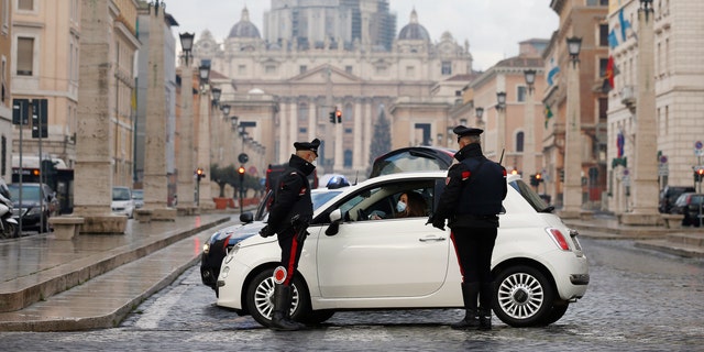Italian Carabinieri officers check vehicles in front of St. Peter's Basilica at the Vatican, Thursday, Dec. 24, 2020. Italians are easing into a holiday season full of restrictions, and already are barred from traveling to other regions except for valid reasons like work or health. Starting Christmas eve, travel beyond city or town borders also will be blocked, with some allowance for very limited personal visits in the same region. (Cecilia Fabiano/LaPresse via AP)