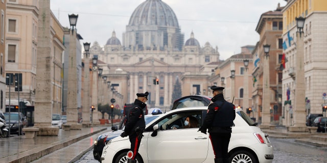 Italian Carabinieri officers check vehicles in front of St. Peter's Basilica at the Vatican, Thursday, Dec. 24, 2020. Italians are easing into a holiday season full of restrictions, and already are barred from traveling to other regions except for valid reasons like work or health. Starting Christmas eve, travel beyond city or town borders also will be blocked, with some allowance for very limited personal visits in the same region. (Cecilia Fabiano/LaPresse via AP)