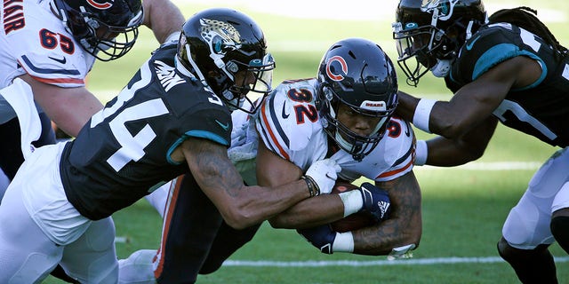 Chicago Bears running back David Montgomery (32) runs for an 8-yard gain as he is tackled by Jacksonville Jaguars cornerback Greg Mabin, left, and cornerback Tre Herndon, right, during the second half of an NFL football game, Sunday, Dec. 27, 2020, in Jacksonville, Fla. (AP Photo/Stephen B. Morton)