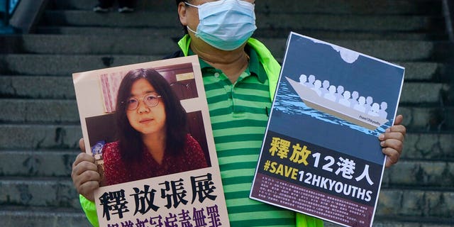 A pro-democracy activist holds placards with the picture of Chinese citizen journalist Zhang Zhan outside the Chinese central government's liaison office, in Hong Kong. (AP Photo/Kin Cheung)