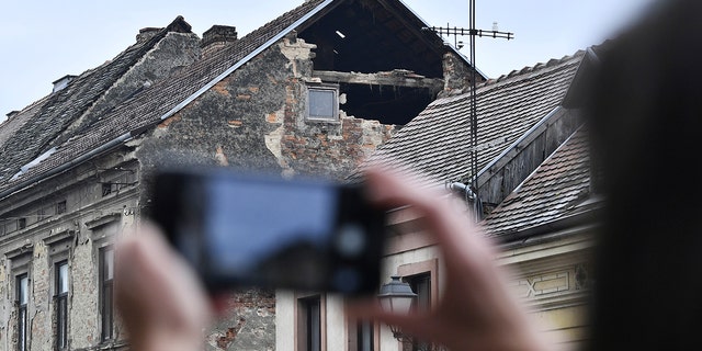 A resident takes a photograph of the damage caused by an earthquake in Sisak, Croatia, Monday, Dec. 28, 2020. A moderate earthquake has hit central Croatia near its capital of Zagreb, triggering panic and some damage south of the city. There were no immediate reports of injuries. (AP Photo)