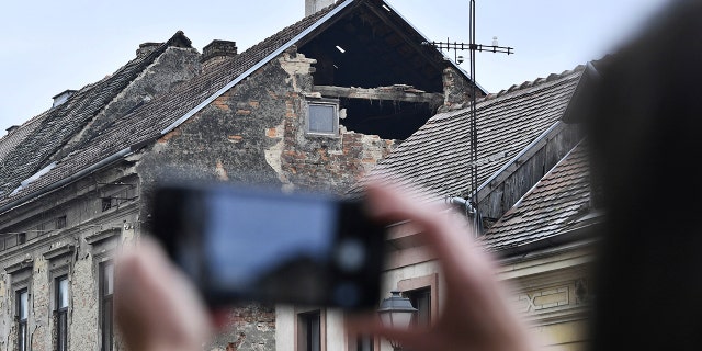 Un residente scatta una fotografia dei danni causati da un terremoto a Sisak, Croazia, Lunedi, Dic. 28, 2020. Un moderato terremoto ha colpito la Croazia centrale vicino alla sua capitale Zagabria, scatenando il panico e alcuni danni a sud della città. Non ci sono state segnalazioni immediate di feriti. (Foto AP)