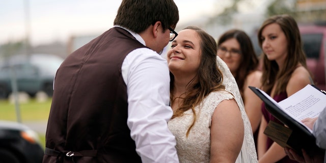 Emily and Taylor Pascale kiss after exchanging vows at their wedding outside the home of Taylor's parents in Grand Lake, Louisiana, which was heavily damaged from Hurricanes Laura and Delta. (AP Photo/Gerald Herbert)