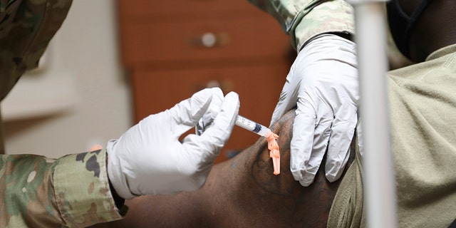 Sgt. Parmer Smith, 129 medical detachment, administers one of the first COVID-19 vaccines to Navy Petty Officer 2nd Class John London, a Hospital Corpsman, SOCKOR Medics, at Brian D. Allgood Army Community Hospital at U.S. Army Garrison Humphreys, in Pyeongtaek, South Korea Tuesday, Dec. 29, 2020. (Spc. Erin Conway/United States Forces Korea vis AP)