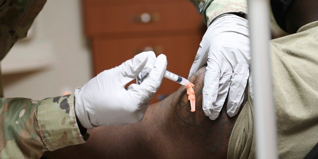 Sgt. Parmer Smith, 129 distacco medico, somministra uno dei primi vaccini COVID-19 al Sottufficiale di seconda classe della Marina John London, un Hospital Corpsman, Calzini medici, presso Brian D. Allgood Army Community Hospital negli Stati Uniti. Army Garrison Humphreys, a Pyeongtaek, South Korea Tuesday, Dic. 29, 2020. (Spc. Erin Conway/United States Forces Korea vis AP)