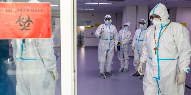 A Russian Orthodox Church priest, 对, leaves a red zone after visiting patients suspected of having coronavirus at a hospital in Kommunarka, outside Moscow, 俄国, 星期一, 十二月. 28, 2020. (Sophia Sandurskaya, Moscow News Agency photo via AP)