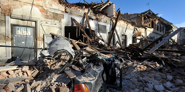 A view of remains of a car covered by debris and buildings damaged in an earthquake in Petrinja, Croatia, Tuesday, Dec. 29, 2020. A strong earthquake has hit central Croatia and caused major damage and at least one death and 20 injuries in a town southeast of the capital Zagreb. (AP Photo)