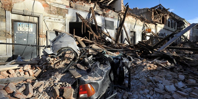 A view of remains of a car covered by debris and buildings damaged in an earthquake in Petrinja, Croatia, Tuesday, Dec. 29, 2020. A strong earthquake has hit central Croatia and caused major damage and at least one death and 20 injuries in a town southeast of the capital Zagreb. (AP Photo)