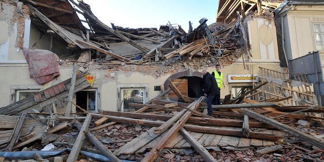 People walk through the rubble from buildings damaged in an earthquake in Petrinja, Croatia, Tuesday, Dec. 29, 2020. A strong earthquake has hit central Croatia and caused major damage and at least one death and some 20 injuries in the town southeast of the capital Zagreb. (AP Photo)