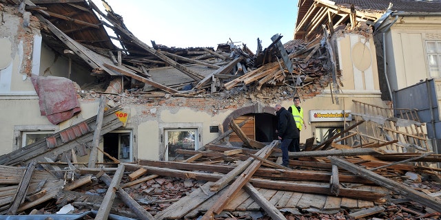 People walk through the rubble from buildings damaged in an earthquake in Petrinja, Croatia, Tuesday, Dec. 29, 2020. A strong earthquake has hit central Croatia and caused major damage and at least one death and some 20 injuries in the town southeast of the capital Zagreb. (AP Photo)