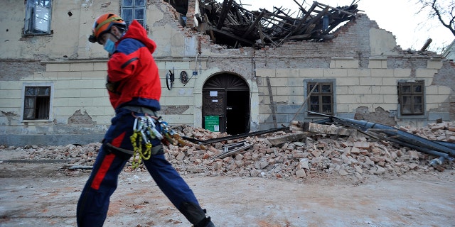 A rescuer walks past a building damaged in an earthquake in Petrinja, Croatia, Tuesday, Dec. 29, 2020. A strong earthquake has hit central Croatia and caused major damage and at least one death and some 20 injuries in the town southeast of the capital Zagreb. (AP Photo)