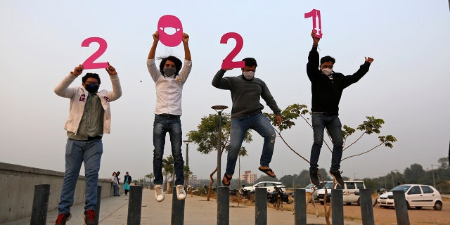 People hold cutouts to welcome the New Year in Ahmedabad, India, Thursday, Dec. 31, 2020. (AP Photo/Ajit Solanki)
