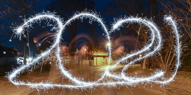 In this long time exposure image, a person appears blurred as he paints 2021 with a sparkler firework to represent the coming year, in the darkness on New Year's Eve, in Briesen, Germany, late Thursday Dec. 31, 2020. (Patrick Pleul/dpa via AP)