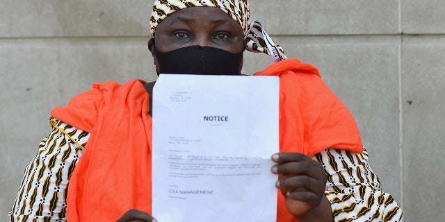 Manty S. Kaba holds up a notice to pay an outstanding balance of her rent from her apartments' property management company, during a protest against evictions and in support of the movement to "cancel rent" outside the Bronx housing court on August 10, 2020 (Angela Weiss/AFP via Getty Images)