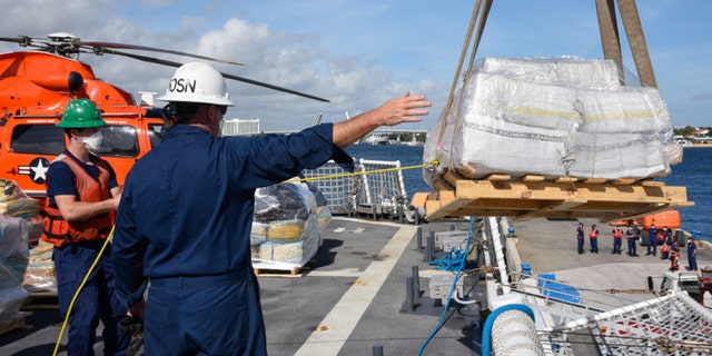 The Coast Guard Cutter James (WMSL 754) crew directs a crane operator from the flight deck offloading approximately 23,000 pounds of cocaine and 8,800 pounds of marijuana at Port Everglades, Florida, Dec. 16, 2020. The James crew patrolled the Eastern Pacific Ocean in support of enhanced counter-narcotics operations in the Western Hemisphere to disrupt transnational crime organizations. (U.S. Coast Guard photo by Petty Officer 3rd Class Jose Hernandez)